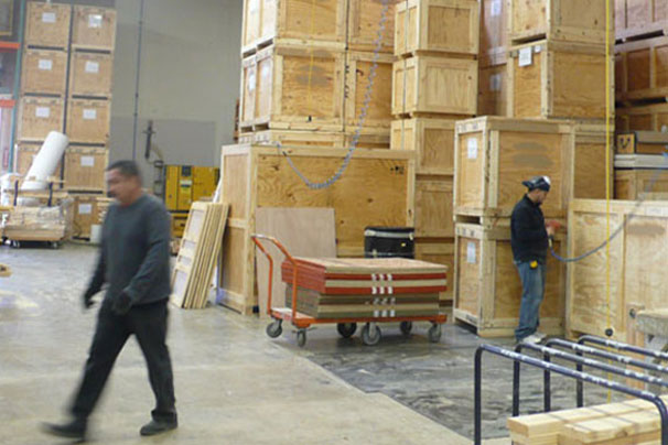 men working in wood shop with crates stacked in background